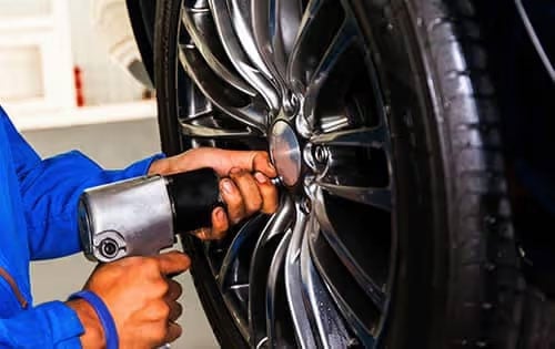 Man Screwing Bolts on Car Tire