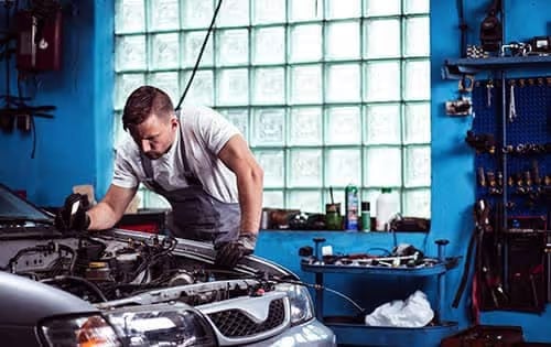 Man Working Under Car Hood in Shop